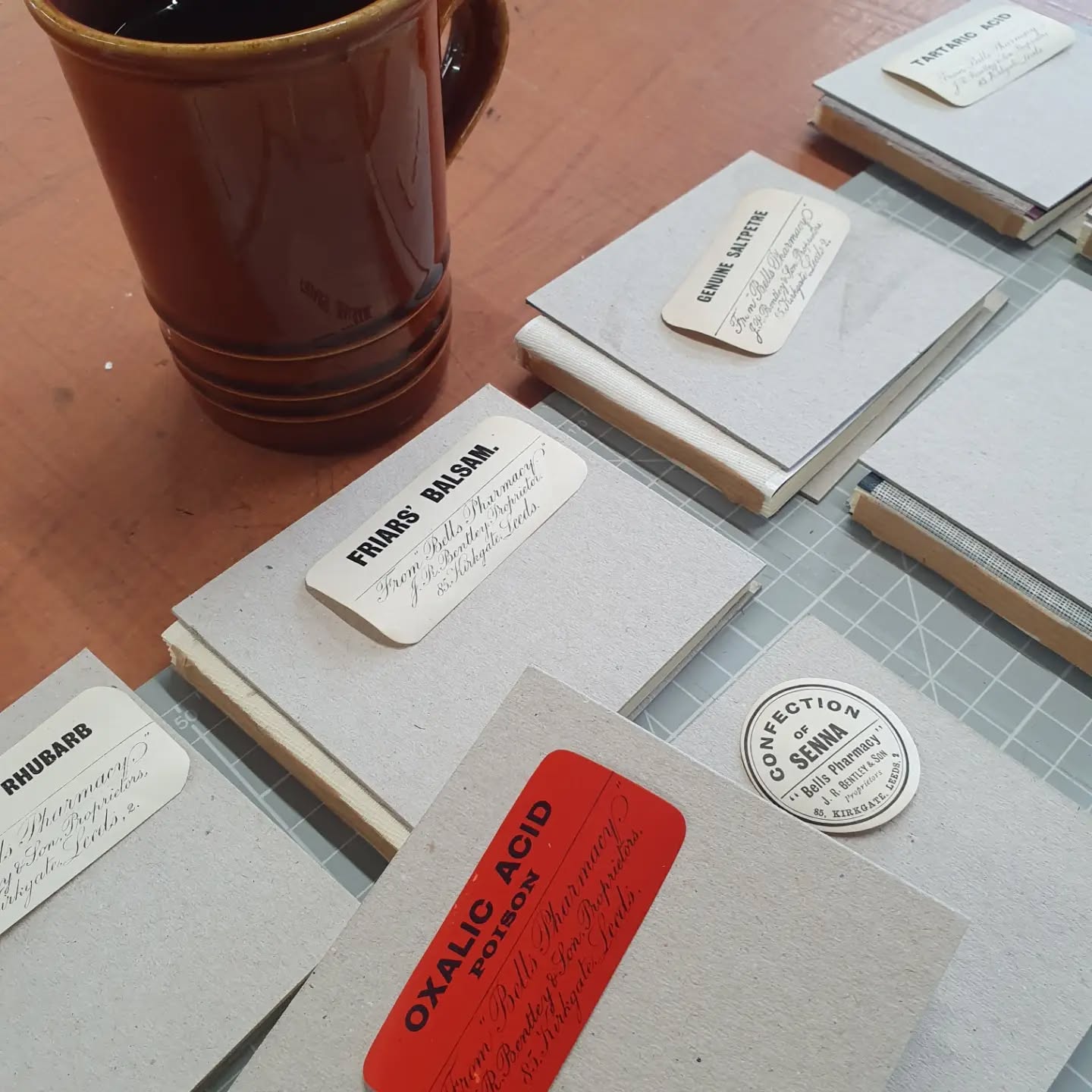A little sneak peek of a collection coming to @fabricationcrafts Leeds soon. Inspired by genuine pharmacy labels printed in Leeds and found in @goodsingeneralstore 

[Image description: books awaiting covering, each one has a different pharmaceutical label resting on it.]