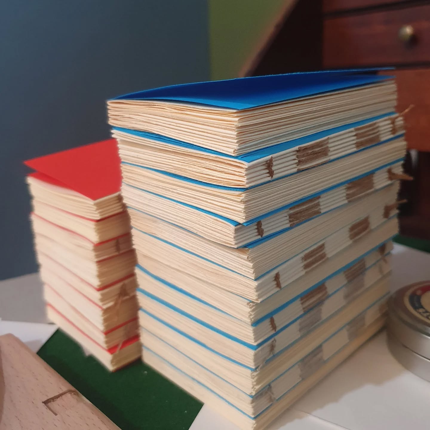 Putting together some little pocket books. Sewn and endpapered, there are still many steps before they become finished books, but nice to get binding again, feels like it's been an age.

Also really loving the wall colour behind my desk now. Both wall colours are from @seagullspaint, the blue has been there a while and was specially mixed, the green I picked up last month and I am so glad I did. It's definitely boosted my mood when in here. Cost me all of £3. Expect a lot more sexy book shots against this new fancy backdrop.

[Image description: a stack of small books awaiting covers on a desk.]