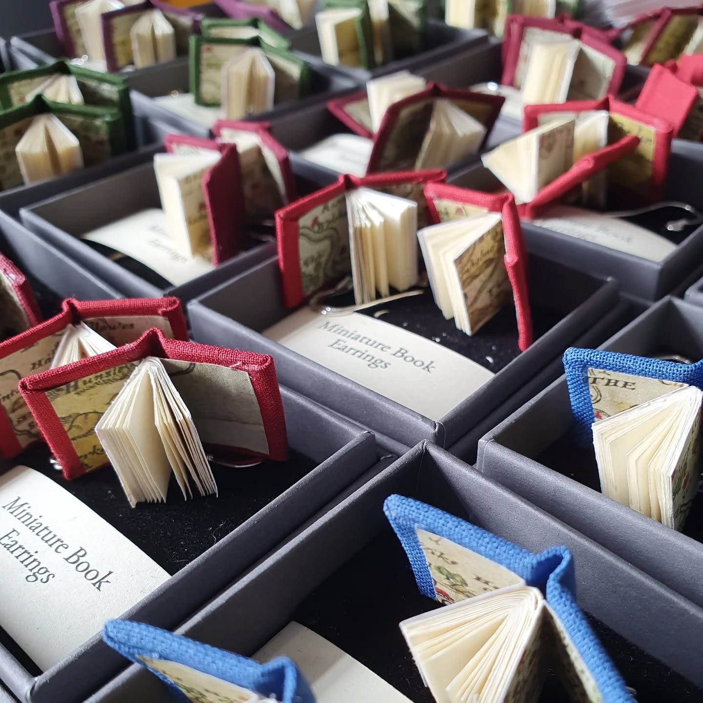 Tiny books getting one step closer to finished, after which they will wing their way to @bronteparsonagemuseum shop.

[Image description: pairs of tiny books laid out in boxes with jewellery fittings.]