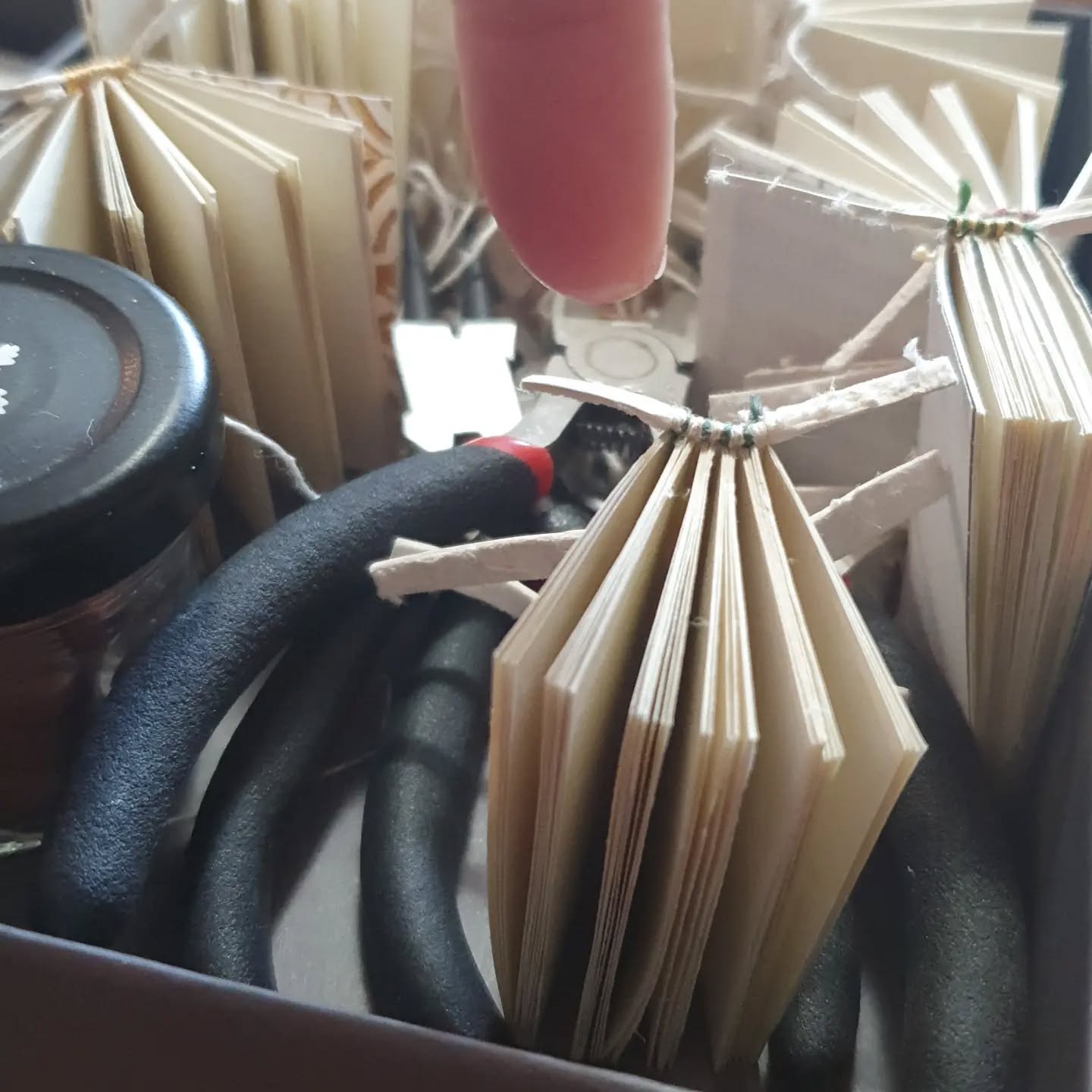 Second batch of teeeeny books for the @imc_leeds craft fair pre-covering. This year, sewn on alum taw instead of cord for added fanciness. Also teeny tiny striped endbands. See the finished product on Wednesday.

[Image description: a selection of miniature text blocks, awaiting covering.]