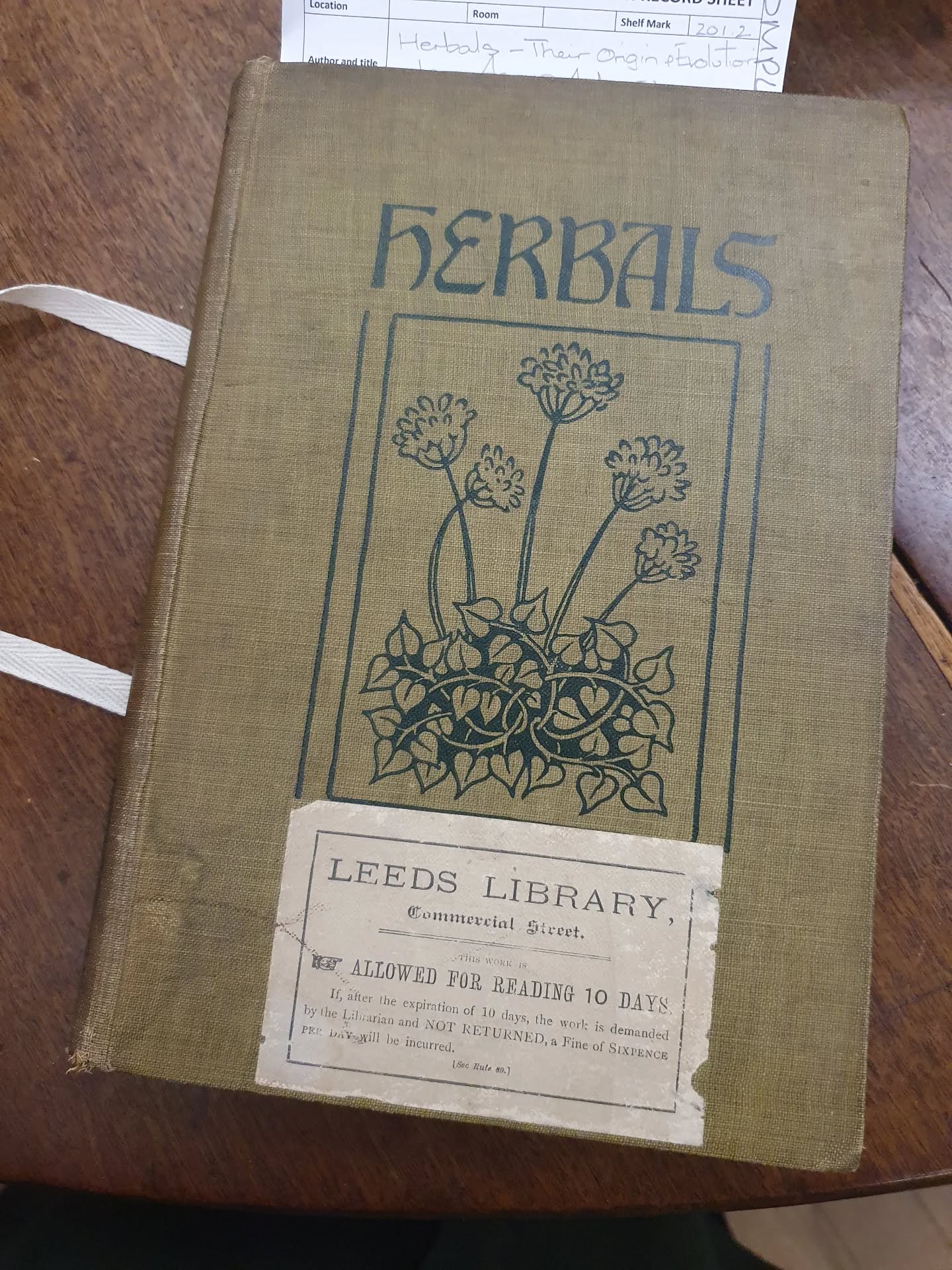 Back at @theleedslibrary with the volunteer book cleaning group this week doing some tear repair and remedial spine stabilising. Including an in-depth look through the repair pile to help them work out which books not to touch. We managed to empty the triage box and now have two neat stacks awaiting our next session where we find out how successful the repairs have been. (Note: they only meet once a week or three would find out sooner). Got to have a lovely flick through the book Herbals, which in addition to the text reproduces images from the 15th to the 19th century.

[Image description: a green book cloth bound book, with a dark green image of a flower in a frame with the word herbal above it, impressed into the cover. Below the image is a Leeds Library book label, that tells us that when it was new it could be borrowed for 10 days.]