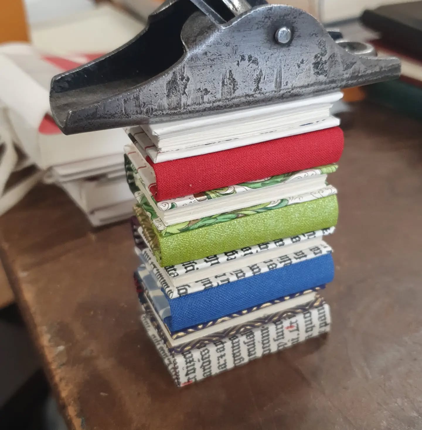 Turned out the only weight I had small enough in the workshop for this tiny batch of books was a thumb plane I use to shape wooden book boards 😅 
All freshly made for the @imc_leeds next up the leather mini tomes...

[Image description: a small stack of 8 miniature books resting under a thumb plane.]