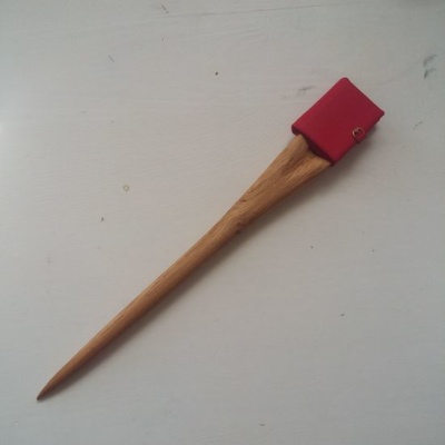 A picture of a wooden hairstick with a miniature book on the top