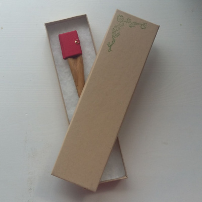 Picture of a wooden hairstick with miniature book attached, displayed in a box