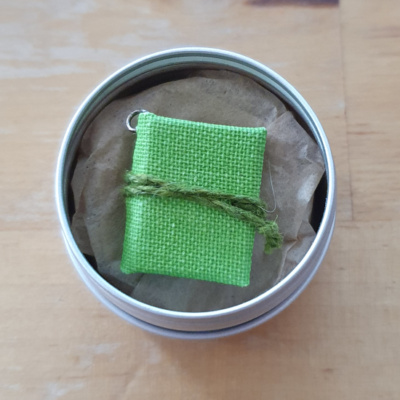 an apple green (or lime green) miniature book charm in a metal tin.
