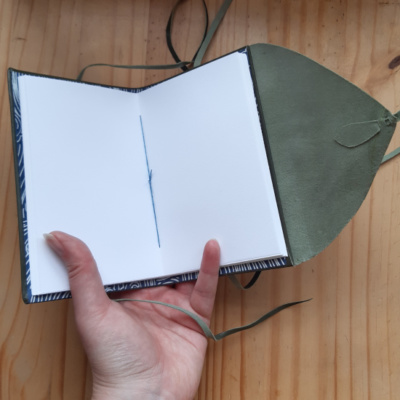 The notebook open to show off the blue thread and cartridge paper