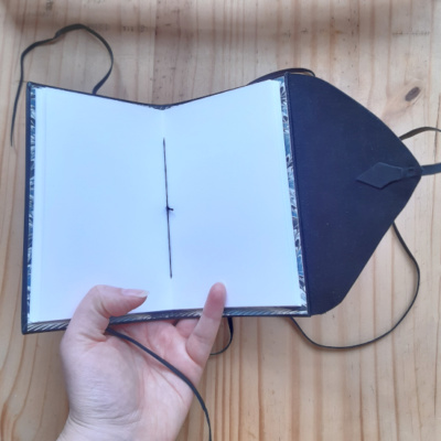 The notebook open to show off the black thread and cartridge paper