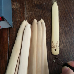 A pile of blank wooden bonefolders being pyrographed