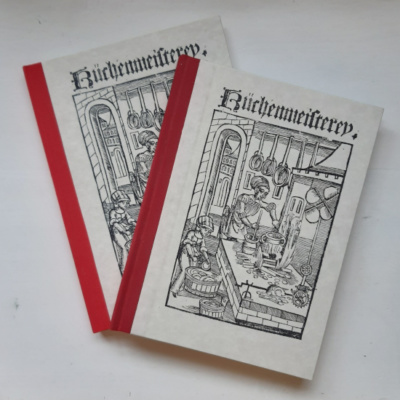 Image showing two books with red spines and paper covers with a woodcut of a medieval kitchen