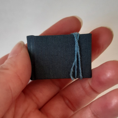 A miniature grey blue book held in a hand