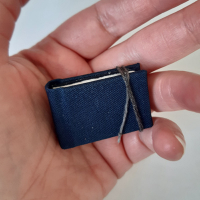 A dark blue miniature book held in a hand