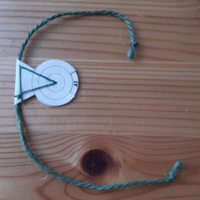 A bookmark with a revolving disc showing roman numerals attached to a long length of green twine.