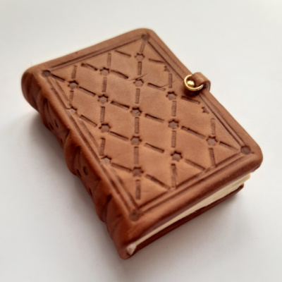 a miniature medieval style book with a line border and diamond quilted pattern blind tooled cover.