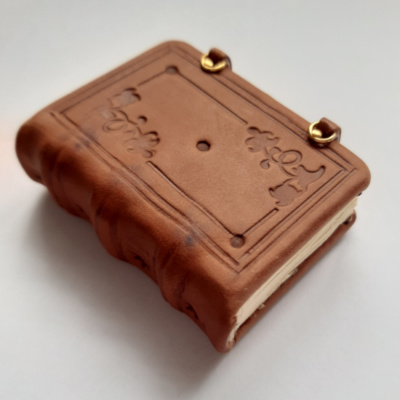 a miniature medieval style book with a border and floral corner motif blind tooled cover.