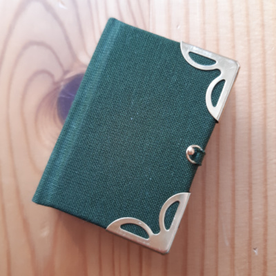 A green miniature book with gold corners and clasp