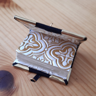 a miniature book with gold and white endpapers