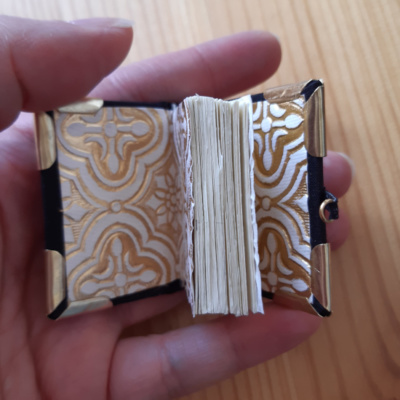 a miniature book with gold and white endpapers