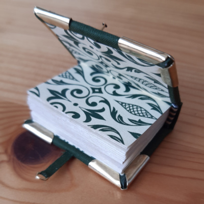 a miniature book with green patterned endpapers