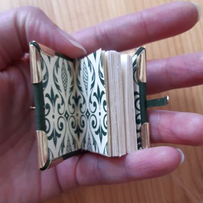 a miniature book with green patterned endpapers