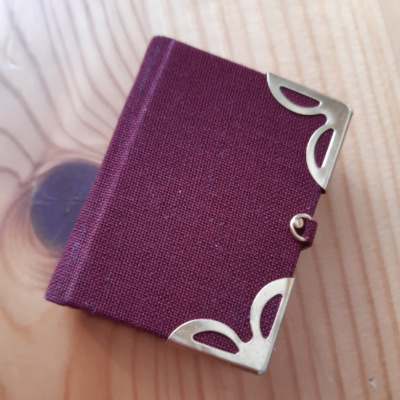 A wine red miniature book with gold corners and clasp