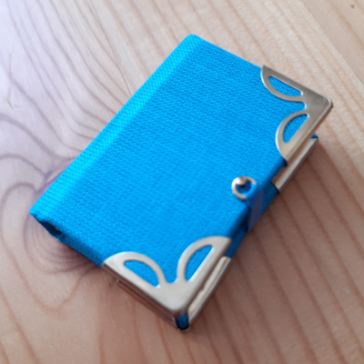 A turquoise miniature book with gold corners and clasp