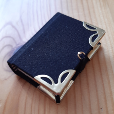 A black miniature book with gold corners and clasp