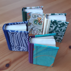 Four different miniature books with cloth spines and paper covers