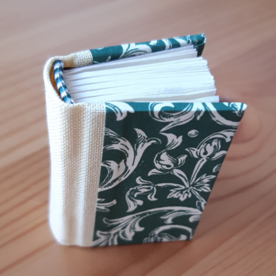 Miniature book with yellow spine and green and white foliage pattern covers