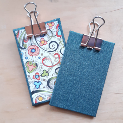 a pair of miniature clipboards showing the green glitter book cloth and Italian swirl decorative paper. Both have a rose gold clip.