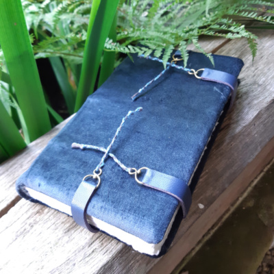 A blue grey velvet covered book with four clasps, two at the foredge, one each at the head and tail.
