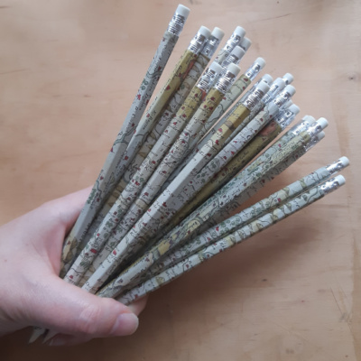 A hand holding a selection of pencils covered in map paper.