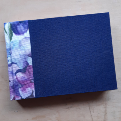 A dark blue book with watercolour fabric spine.