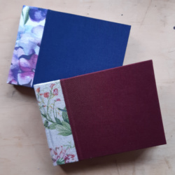 Two books with bookcloth covers and floral watercolour fabric spines.