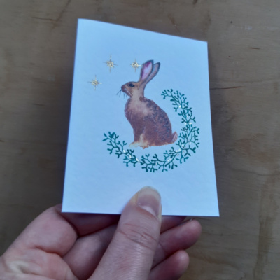 A hare card held to show off sillver and gold spot tooling