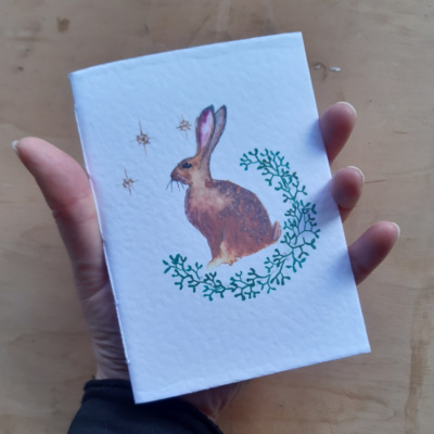 A hand holding a pamphlet with a hare on