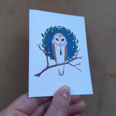 A card held to show the gold tooling on an owl image.