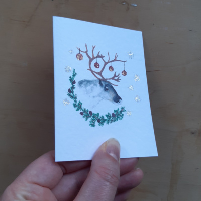 a card held to show the spot foiling on a reindeer image