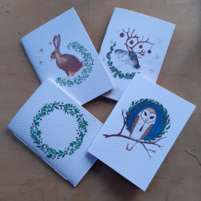 Four pamphlets with winter themed images on, a hare, owl, reindeer, and wreath.