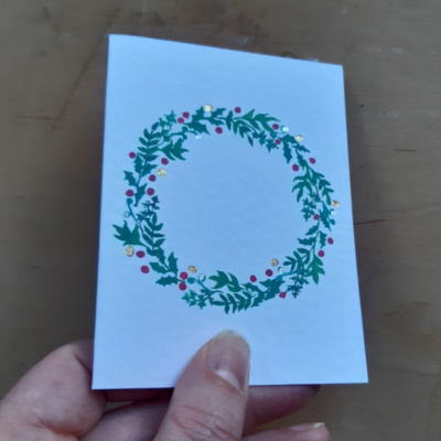 A card held to show off the spot foiling on the wreath image