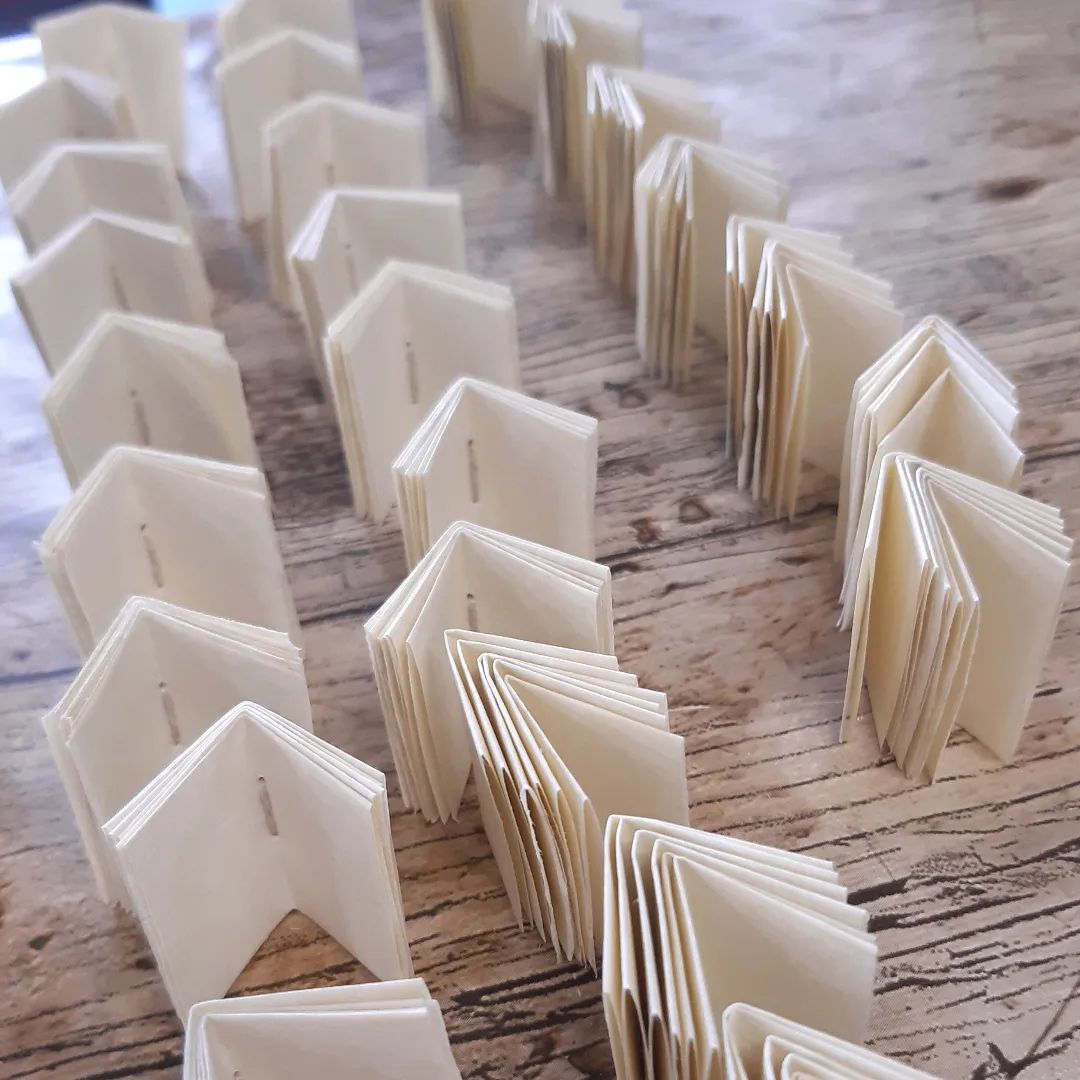 #TinyThursday with rows of mini pamphlets waiting to become book charms.

[Image description: rows of folded and sewn miniature pamphlets on a workbench.]

#MiniatureBooks #TinyBook #WorkInProgress