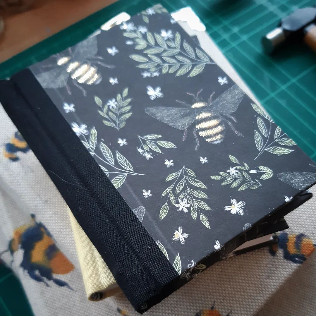 Happy World Bee Day! Here's another close-up of the bee mini collection I've been working on.

[Image description: a close-up of a small notebook with a black spine and bee decorated covers on a stack if bee decorated books.]

#WorldBeeDay2022 #WorldBeeDay #Bees