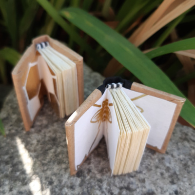 a pair of miniature books opened to reveal bee-themed endpapers