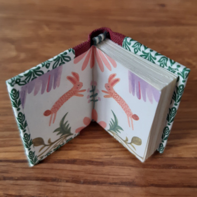 A miniature book open to show the rabbits on the endpapers