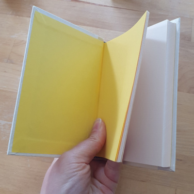 a book held open to show off bright yellow end papers and the cream laid paper pages.