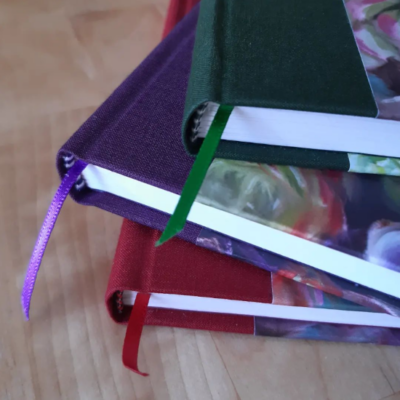 A close up of three spines to show off the coloured book cloth spines with coloured ribbon in a matching colour.