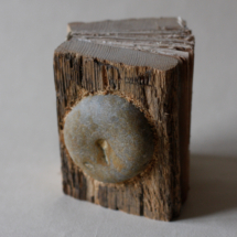A book with wooden covers made out of weathered planks. A stone is embedded into the cover.
