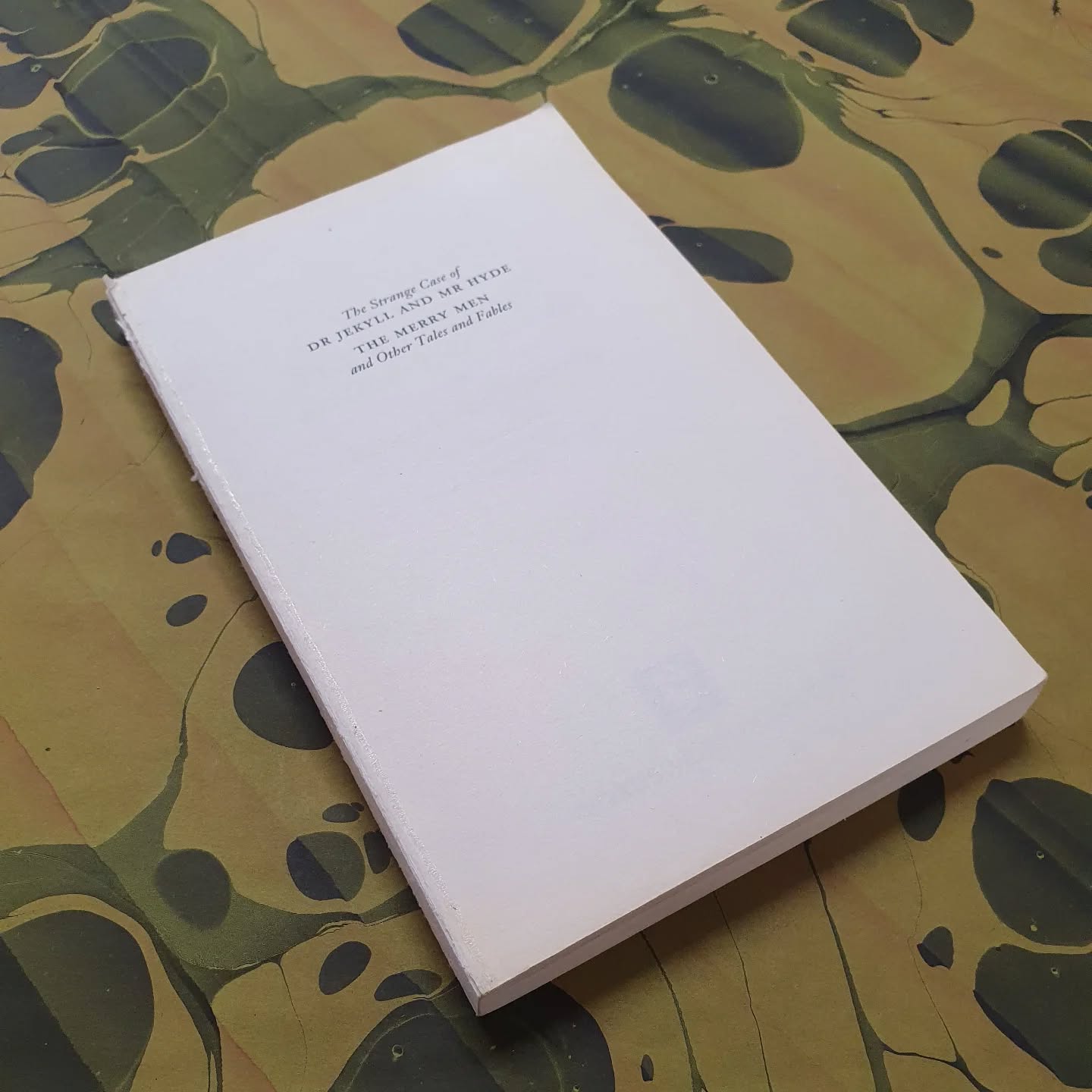 It has been a while since I did a paperback to hardback rebind. It is time... starting with one I've been pondering a good long while as it has sat on my WIP pile - Jekyll and Hyde (and other tales).

(With apologies for using music but this clip fit v nicely.)

[Image description: a coverless paperback lying on green marbled paper.]