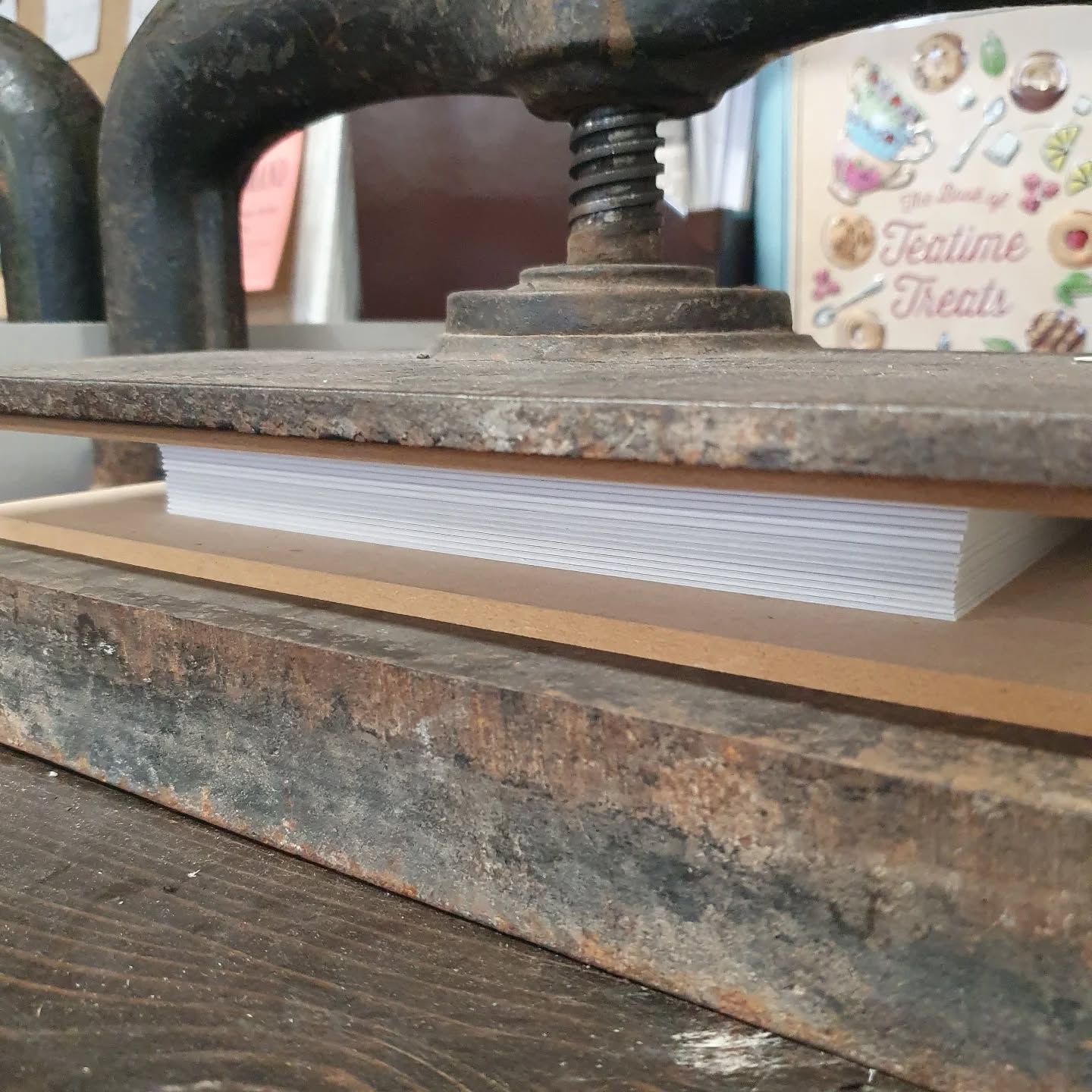 Prepping pages for today's sold out class at the @thackraymuseum 2026 diary pages all prepped and ready to prick and sew. Can't wait to see what the participants come up with design wise.

[Image description: Book pages inside of a nipping press.]