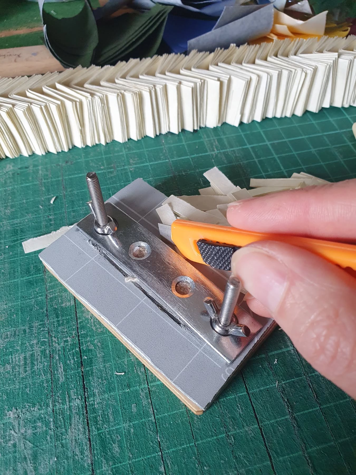 So many tiny books being trimmed on the desk right now. Very grateful for my self made cutting jig. Still some way to go before these start looking like a book.

[Image description: a miniature book in a clamp being trimmed and more waiting their turn.]