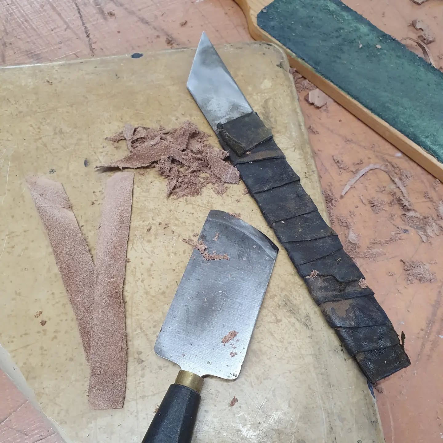 Doing a bit of leather paring which I rarely get to do (as I mostly bind in older styles that didn't do much paring). Every time I do this I'm reminded that the quality of the leather helps (this one pared beautifully) as does the sharpness of your knife. Pictured here are two different styles of paring knife. Both of which I find easier to use than the cobblers knife I learned to pare with. I also on occasion use scalpels if I'm paring something smaller.

Now to book myself on a sharpening course to refresh my skills there...

[Image description: two paring knives, one with a straight edge, one curved, are resting on a broken lithography stone surrounded by leather trimmings.]